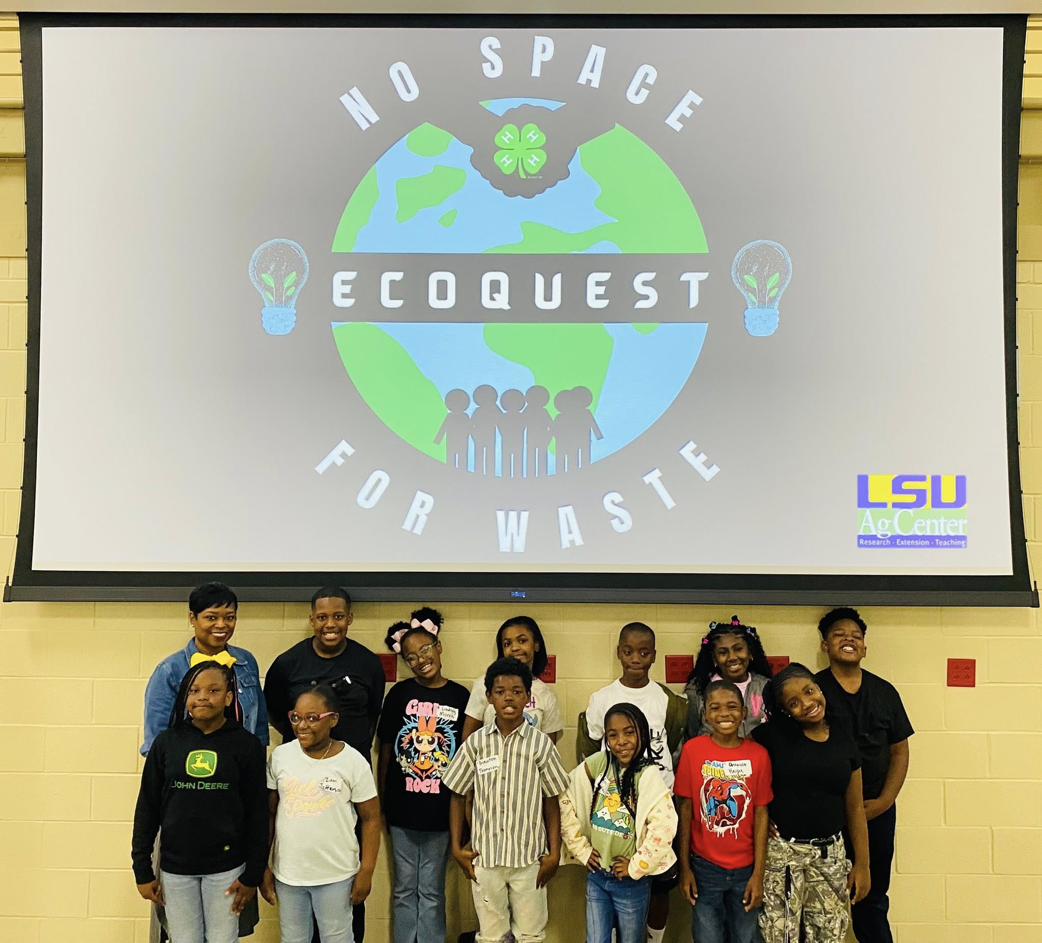 A group of people posing under a screen that says No Space for Waste EcoQuest. LSU AgCenter Research, Extension, Teaching logo.